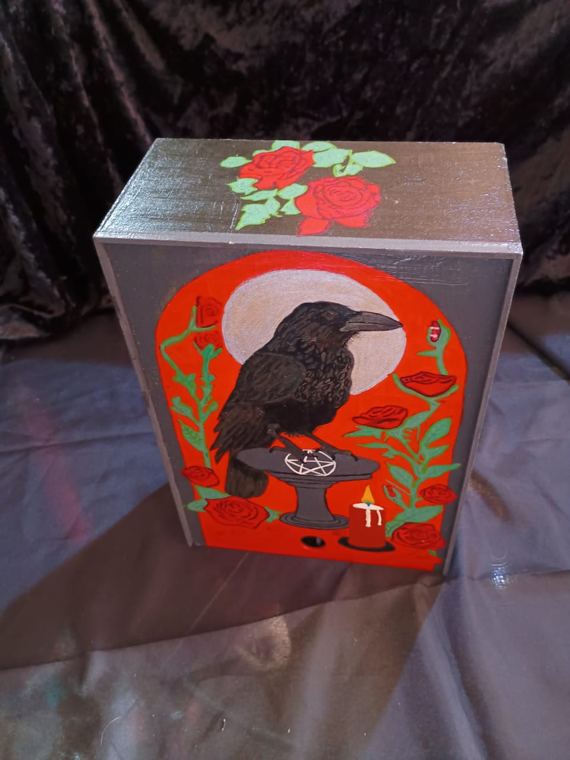 Caja gris con cuervo sobre pentáculo y rosas